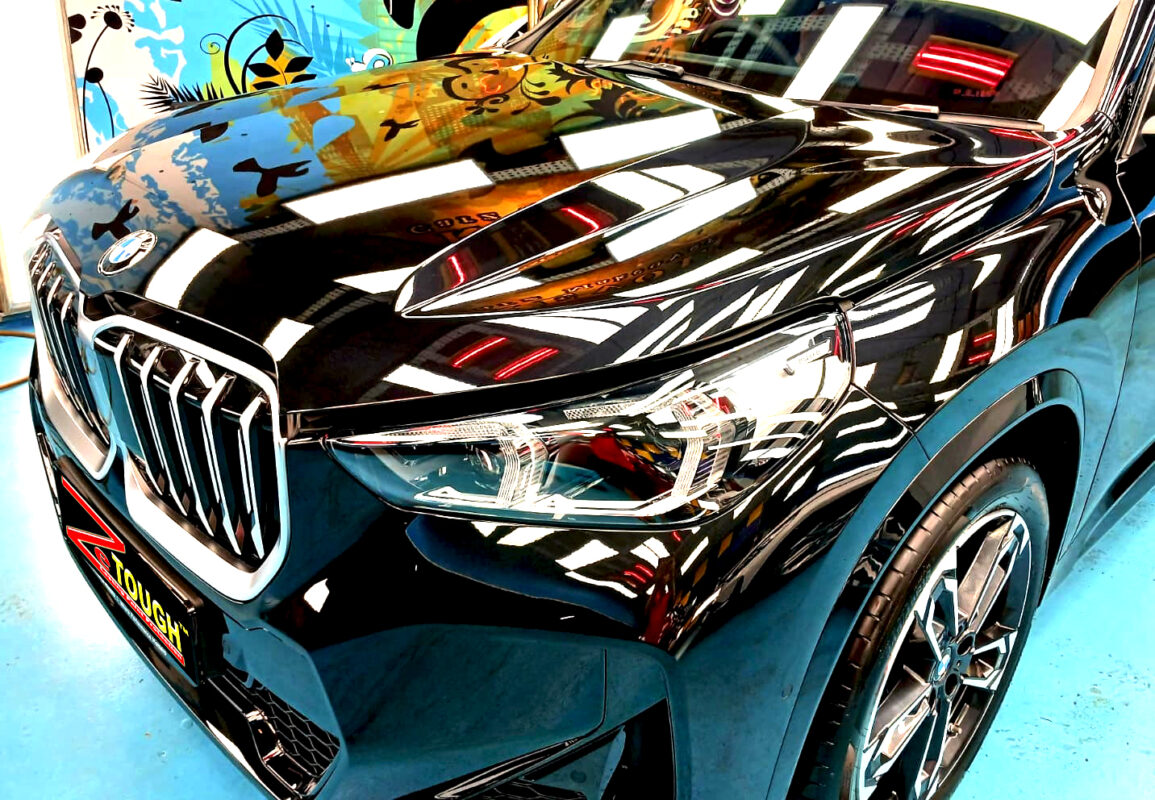 The BMW X1's coated paintwork under workshop lighting.
