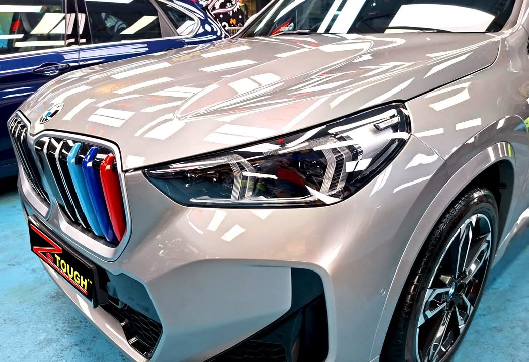 Close-up of the kidney grille with M-colour slats and the headlamp on the grey nose.