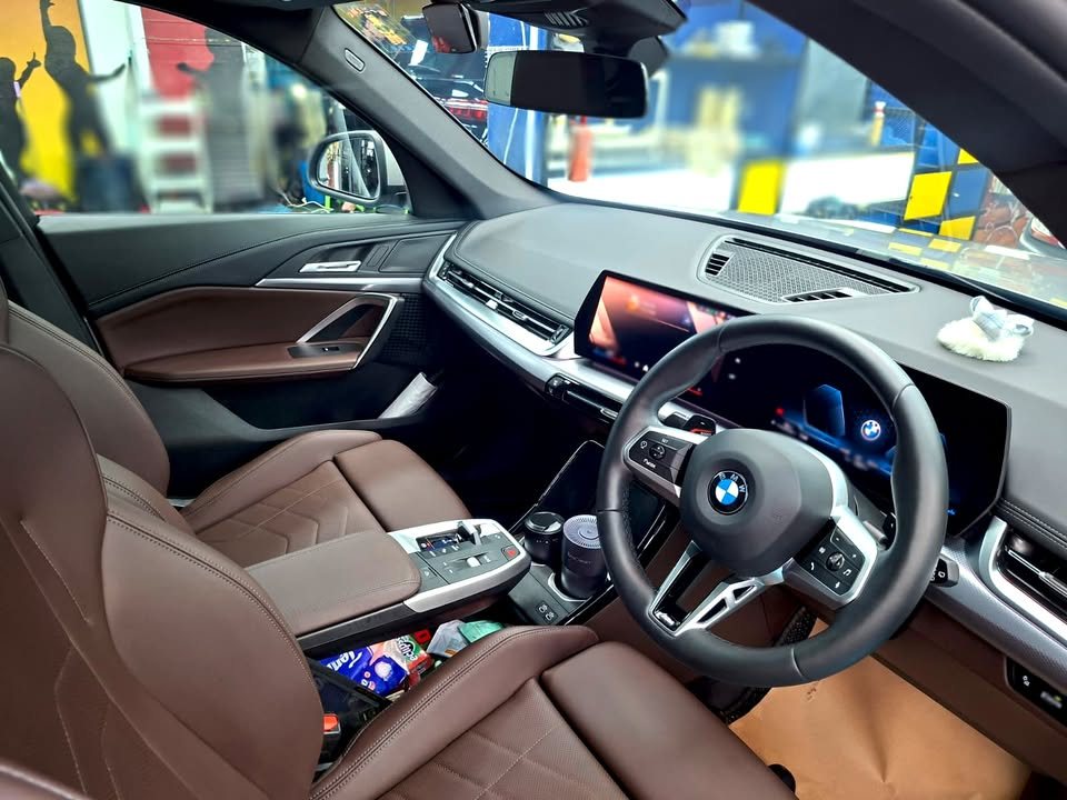 Interior view of the brown leather seats, steering wheel and curved display.