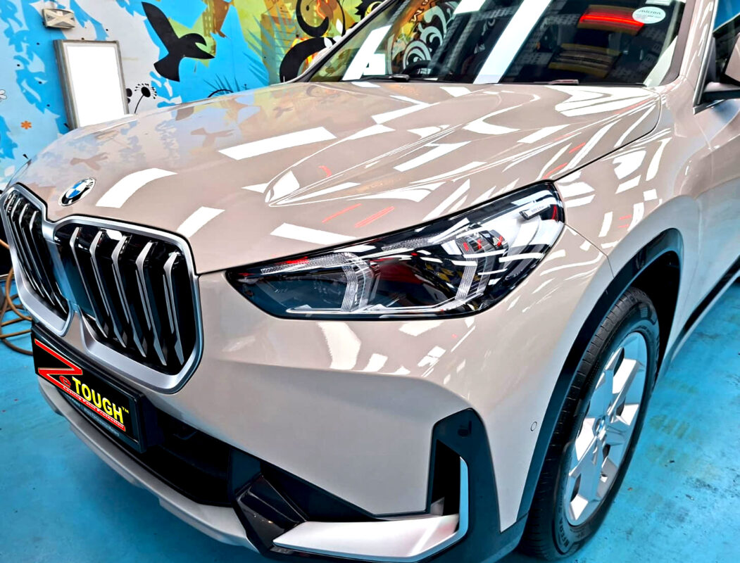 The BMW X1's coated paintwork under workshop lighting.