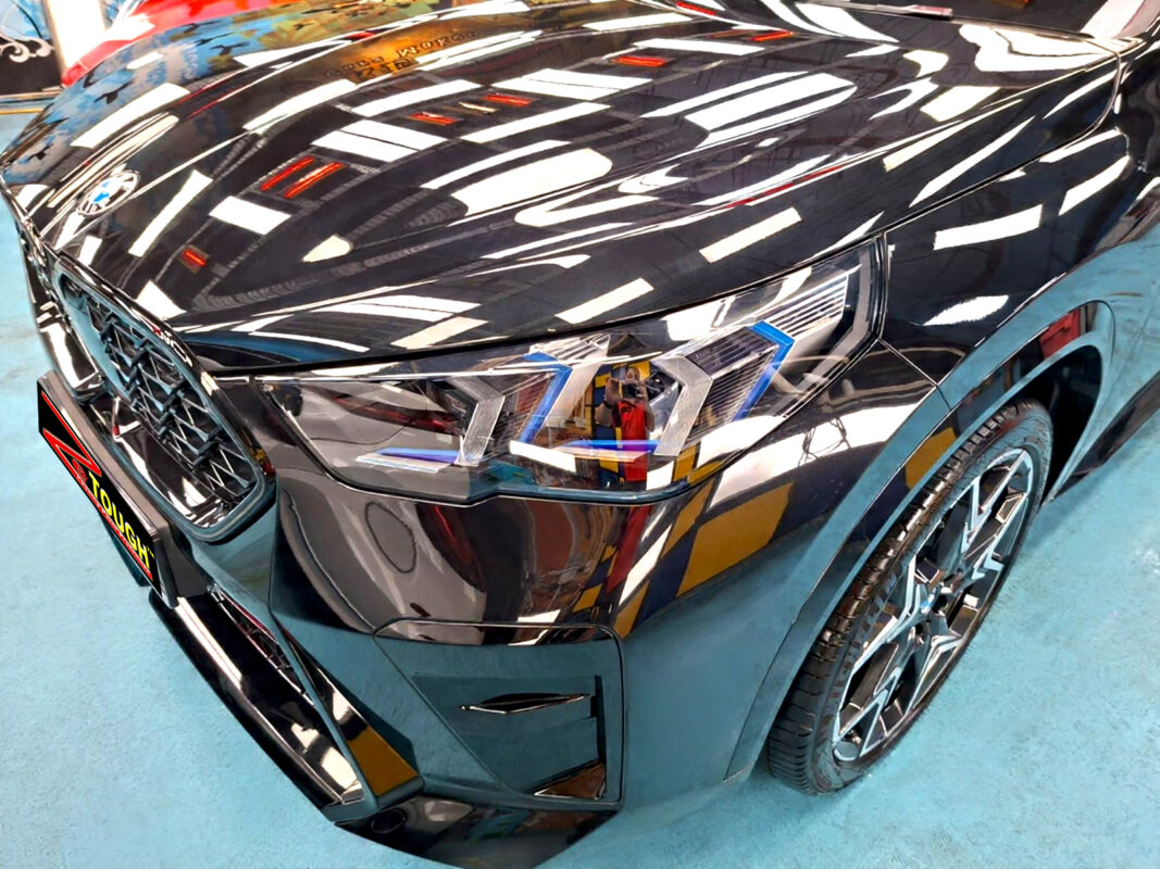The BMW X2's coated paintwork under workshop lighting.