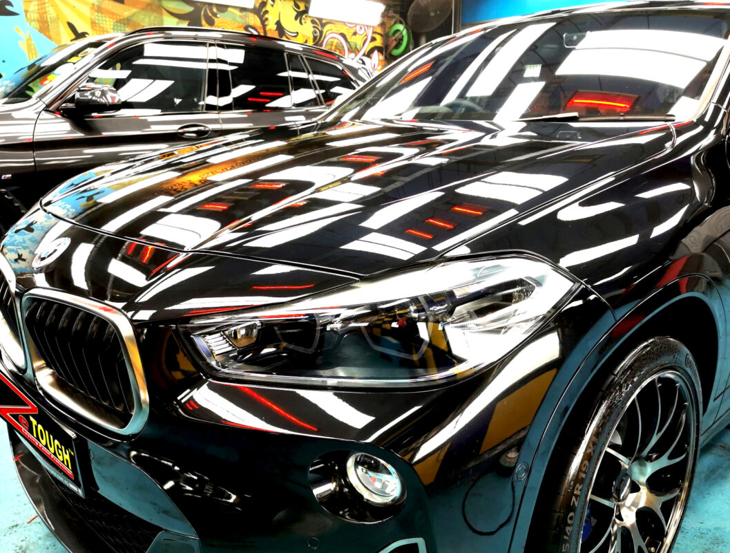 The BMW X2's coated paintwork under workshop lighting.