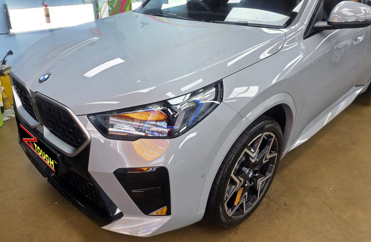 The BMW X2's coated paintwork under workshop lighting.