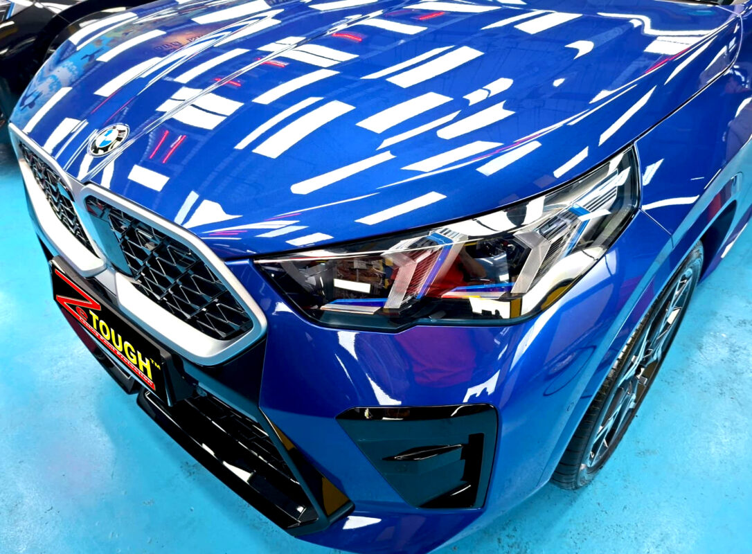 The BMW X2's coated paintwork under workshop lighting.