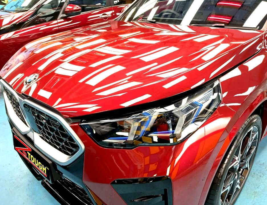 Bonnet, grille and headlight of the red X2 with sharp light reflections.