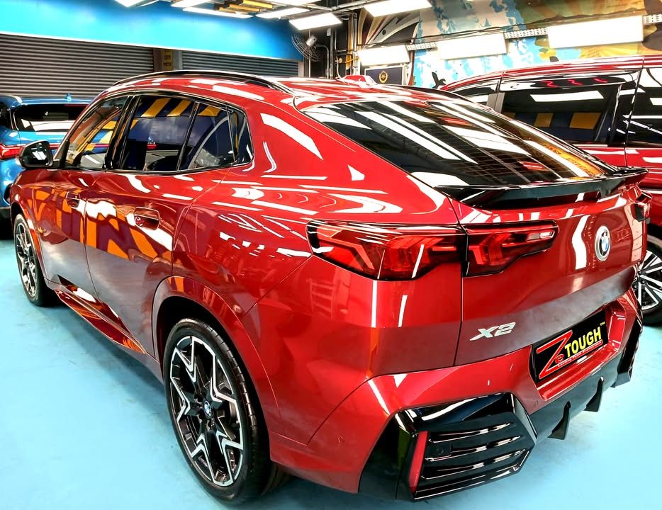 Rear three-quarter view of the red BMW X2 showing the tail lights and X2 badge.