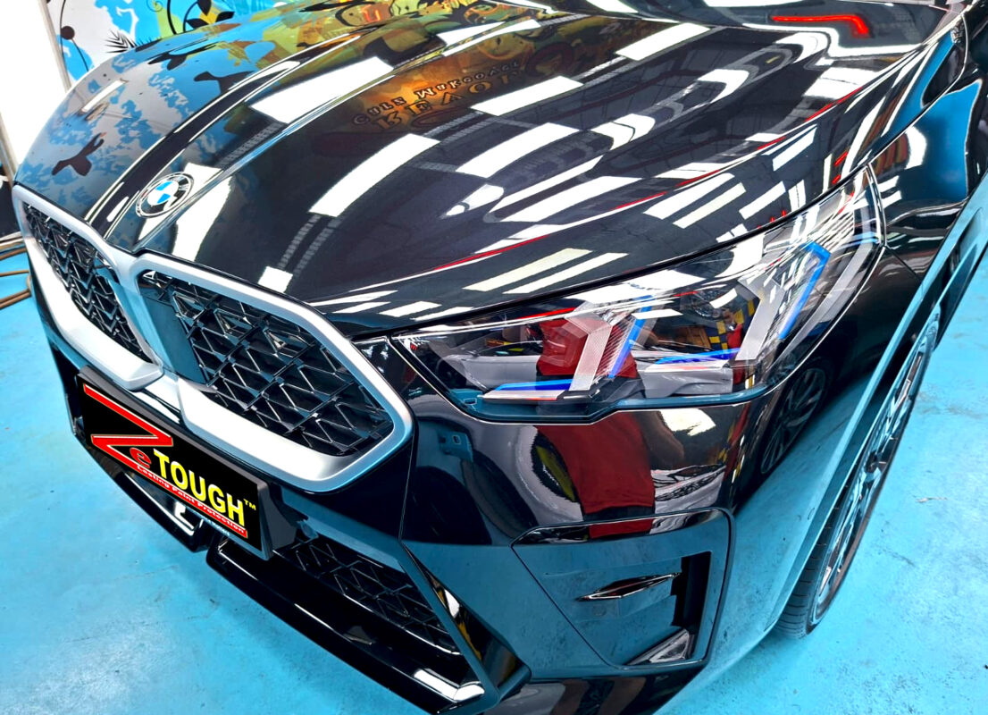The BMW X2's coated paintwork under workshop lighting.