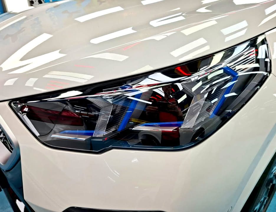 Close view of the BMW X2 headlight and white front bumper.