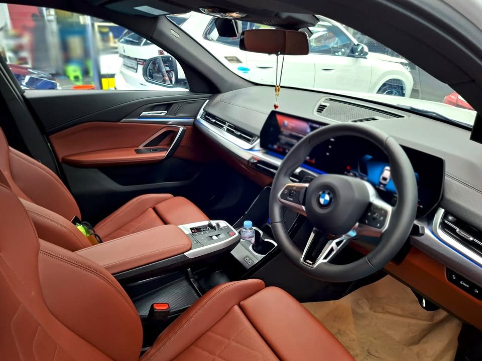 BMW X2 front cabin with brown leather seats and curved screen.