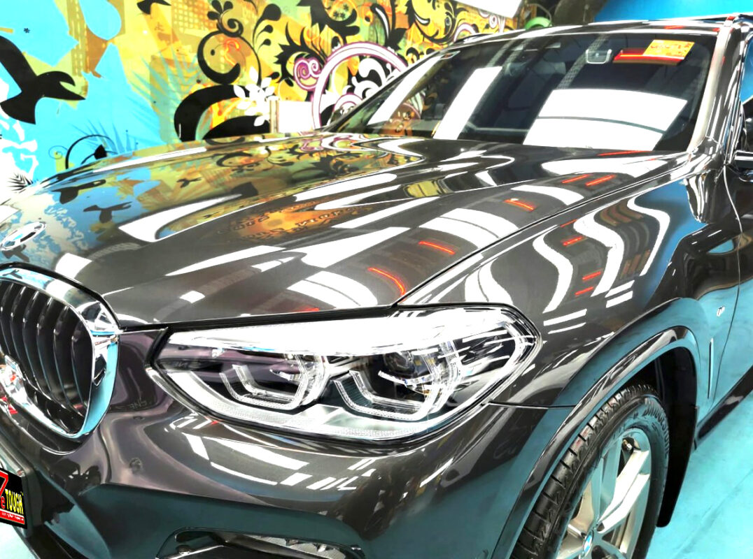 The BMW X3's coated paintwork under workshop lighting.