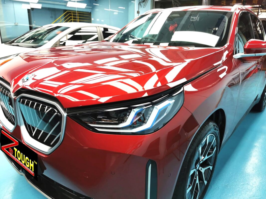 The BMW X3's coated paintwork under workshop lighting.