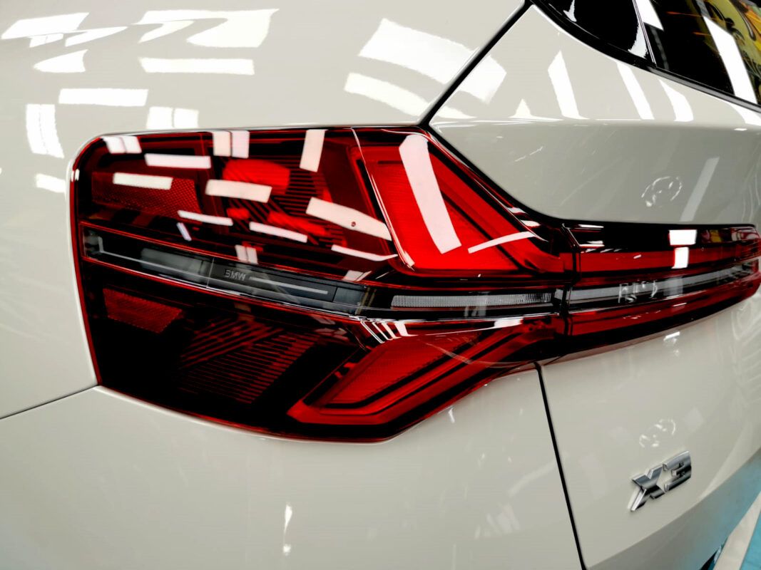 The coated bonnet of the BMW X3 under workshop lighting.