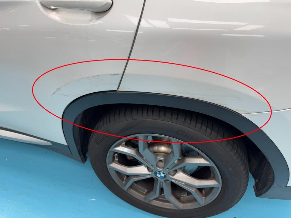 Scuffed paint above the rear wheel arch of the X4, circled in red.