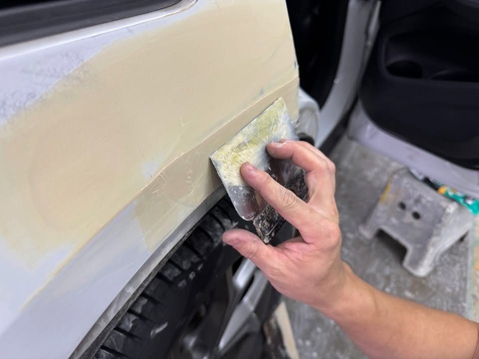 Sanding filler on the X4's rear quarter by the wheel arch.
