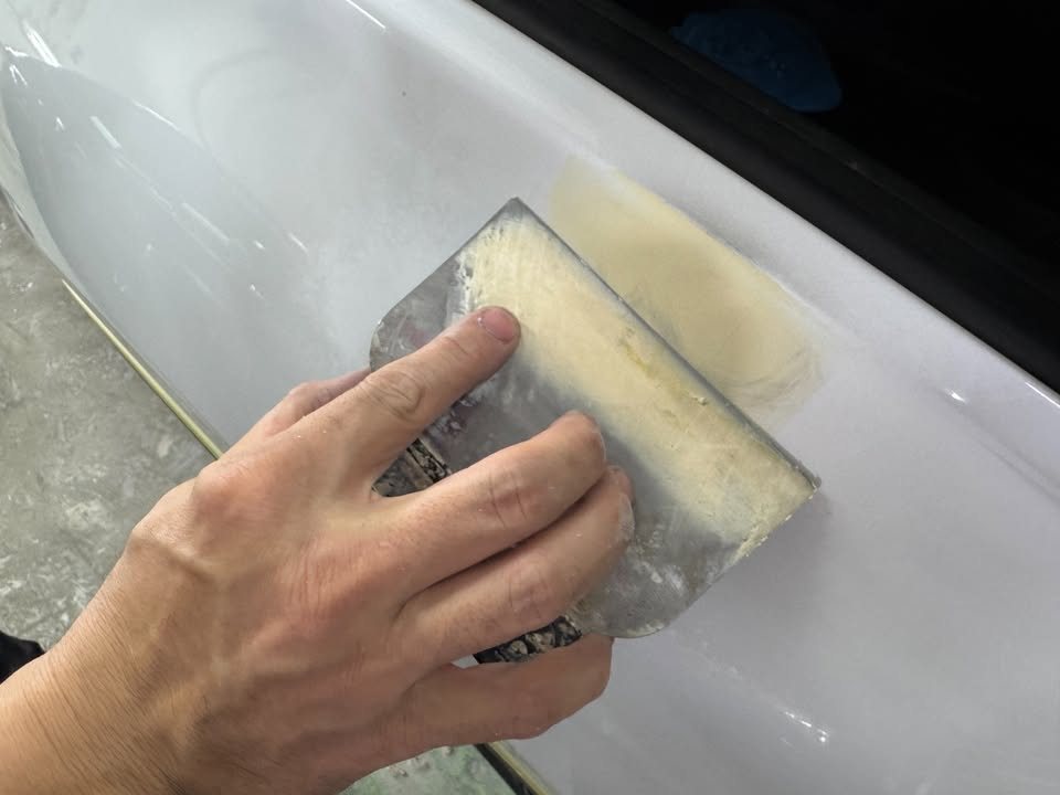 Sanding block levelling filler on the white bodywork.