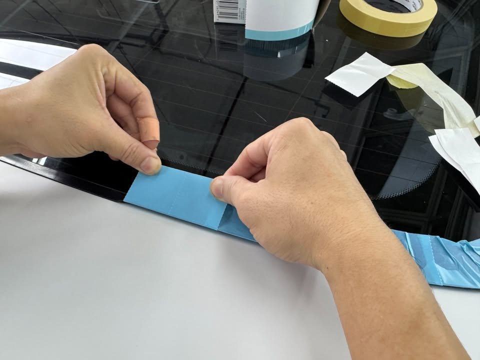 Removing protective tape from the trim below the X4's rear window.