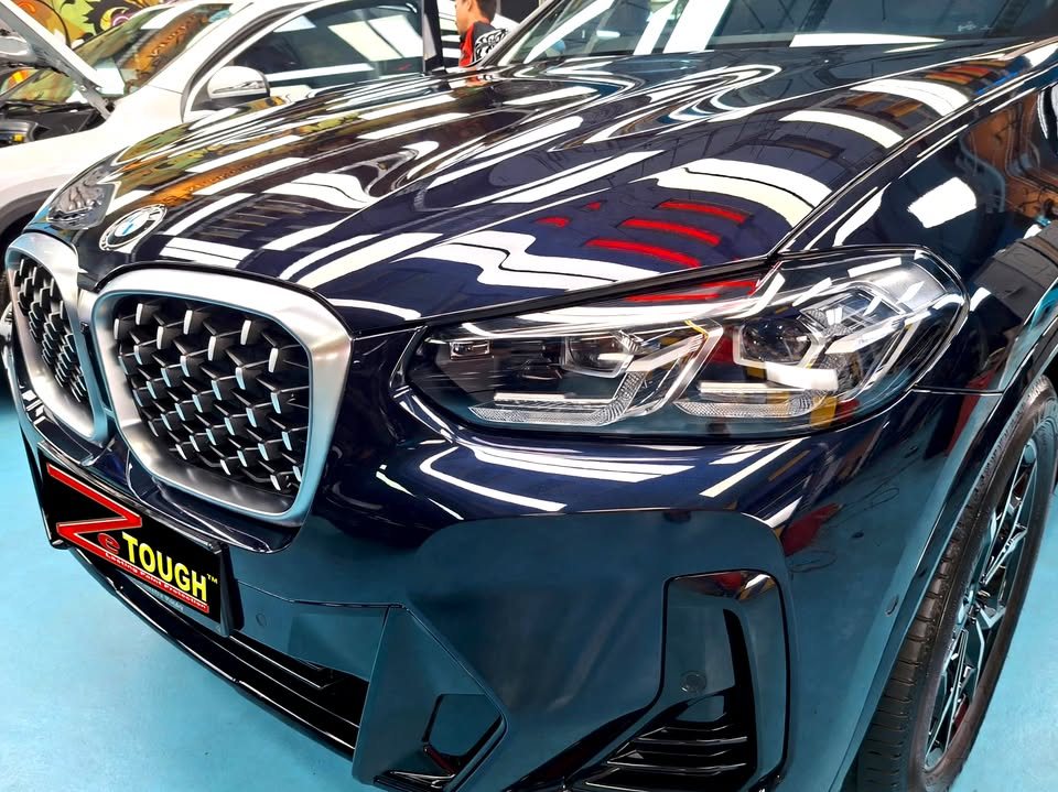 Bonnet, kidney grille and headlight of the dark blue X4 with sharp reflections.