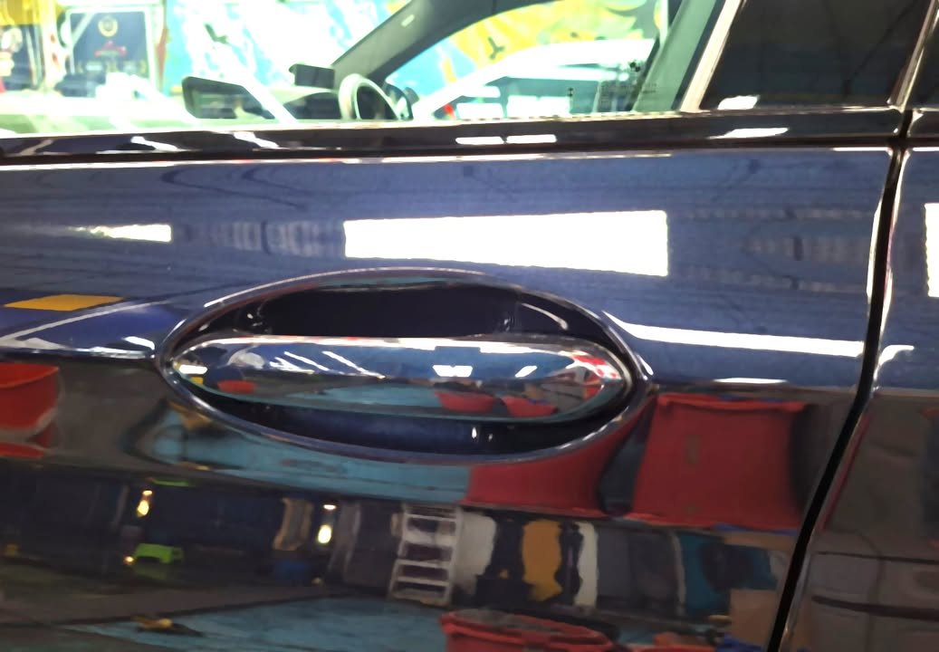 Door handle on the dark blue X4 with a mirror-like reflection in the panel.