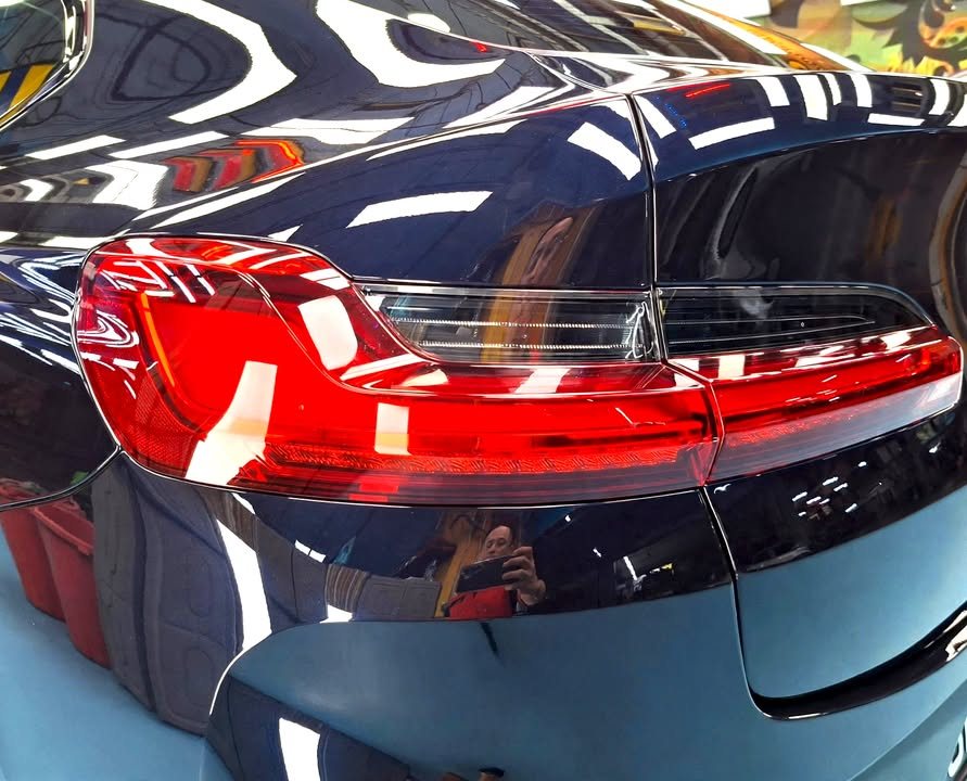 Close-up of the X4 tail light and rear quarter in dark blue paint.