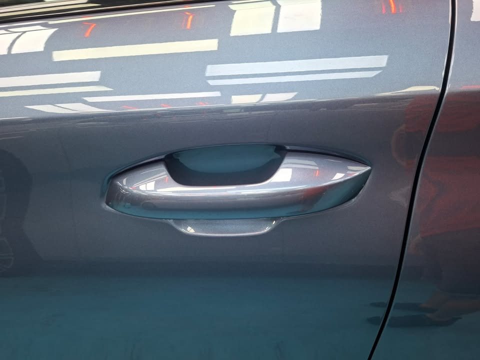Door handle on the blue-grey BYD Atto 3 with reflections across the door panel.
