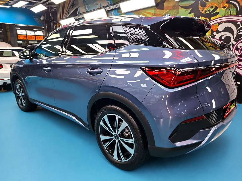 Rear three-quarter view of the blue-grey BYD Atto 3 in the workshop.