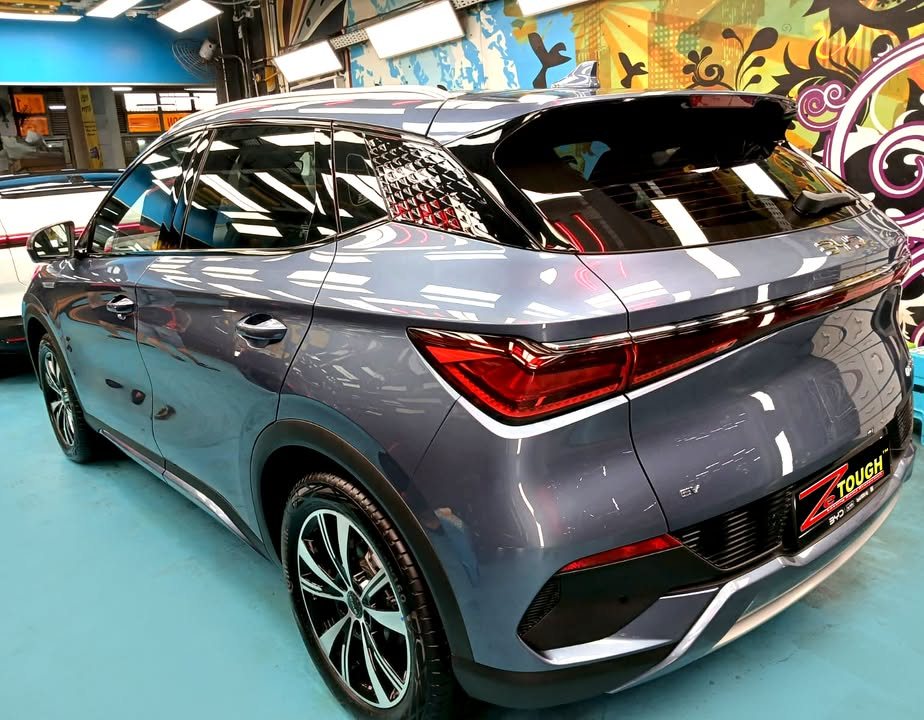 Rear three-quarter view of the grey-blue BYD Atto 3 with its rear light bar and alloy wheel.