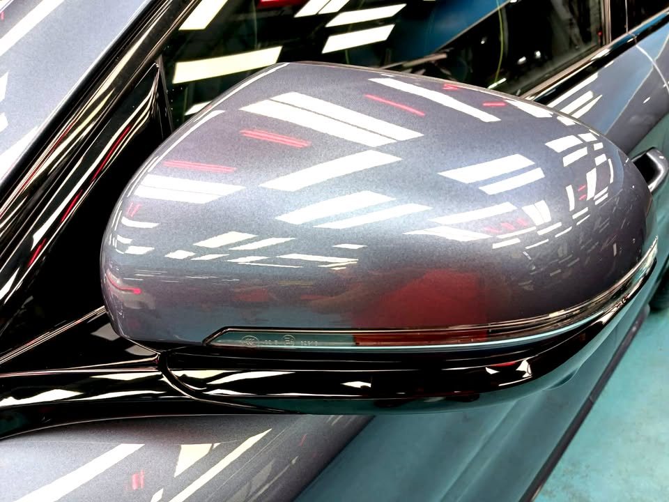 Grey-blue side mirror cap with reflections of the workshop lights.