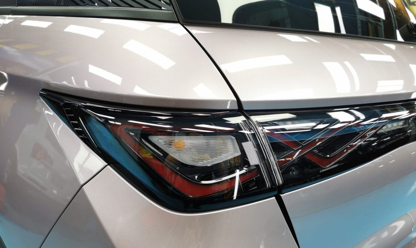 The coated bonnet of the BYD Dolphin Dynamic under workshop lighting.