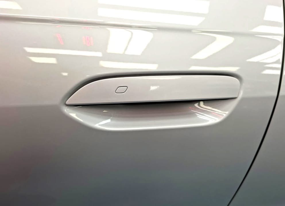 White door panel with a flush handle and light reflections.