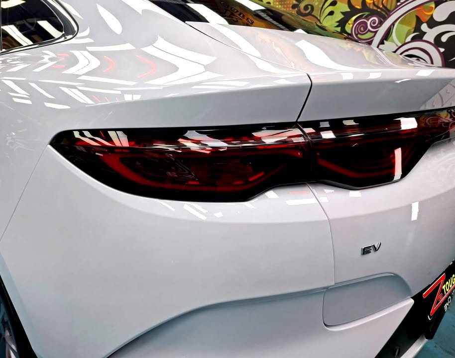 Close-up of the smoked tail light and EV badge on the white rear quarter.