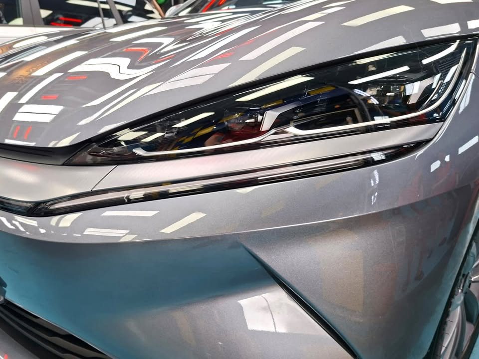 Close-up of the slim headlamp and the sculpted grey front bumper.