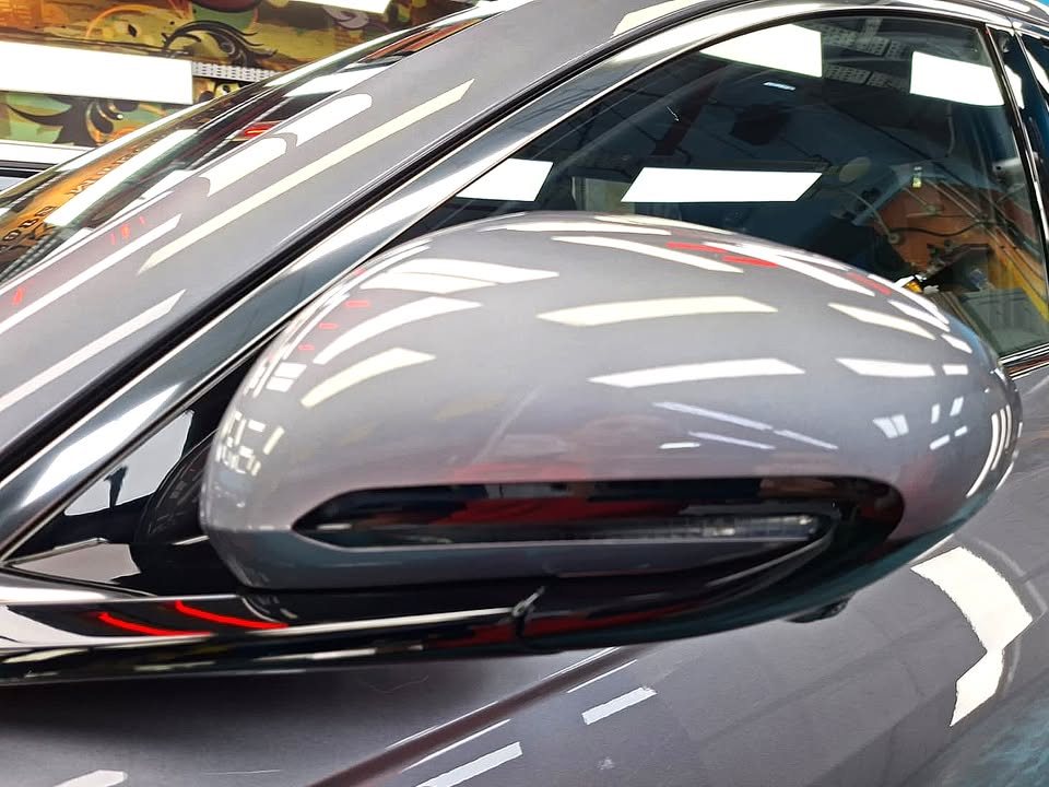 The grey wing mirror with its integrated indicator, reflecting the workshop lights.