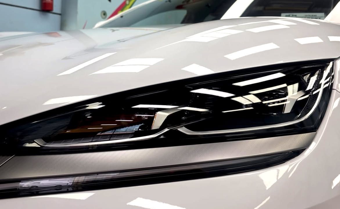 Close-up of the slim headlight below the glossy white bonnet.