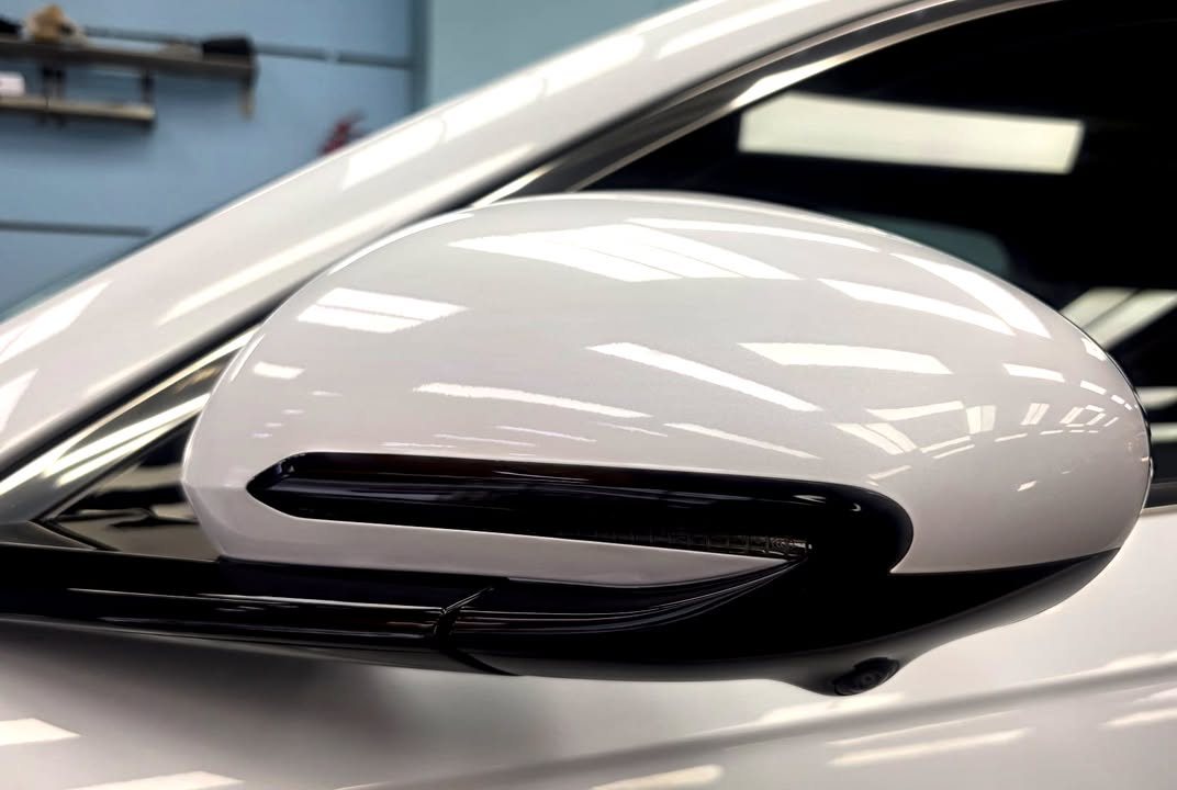 White side mirror cap reflecting the ceiling lights.