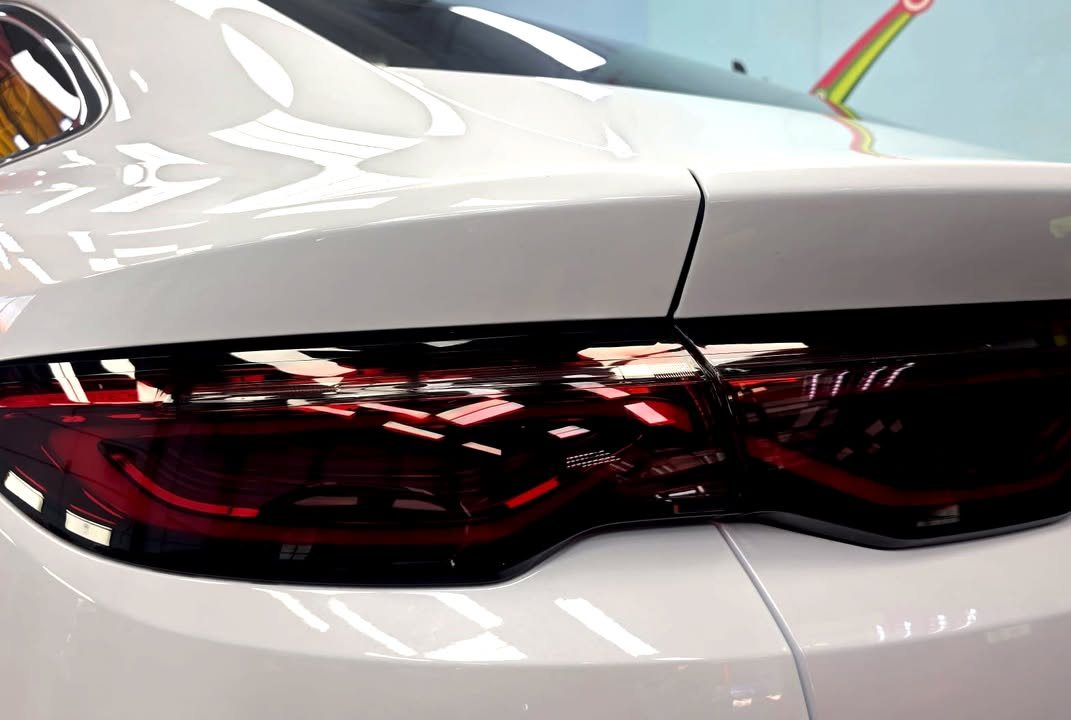 Close-up of the dark red tail light across the white rear quarter.