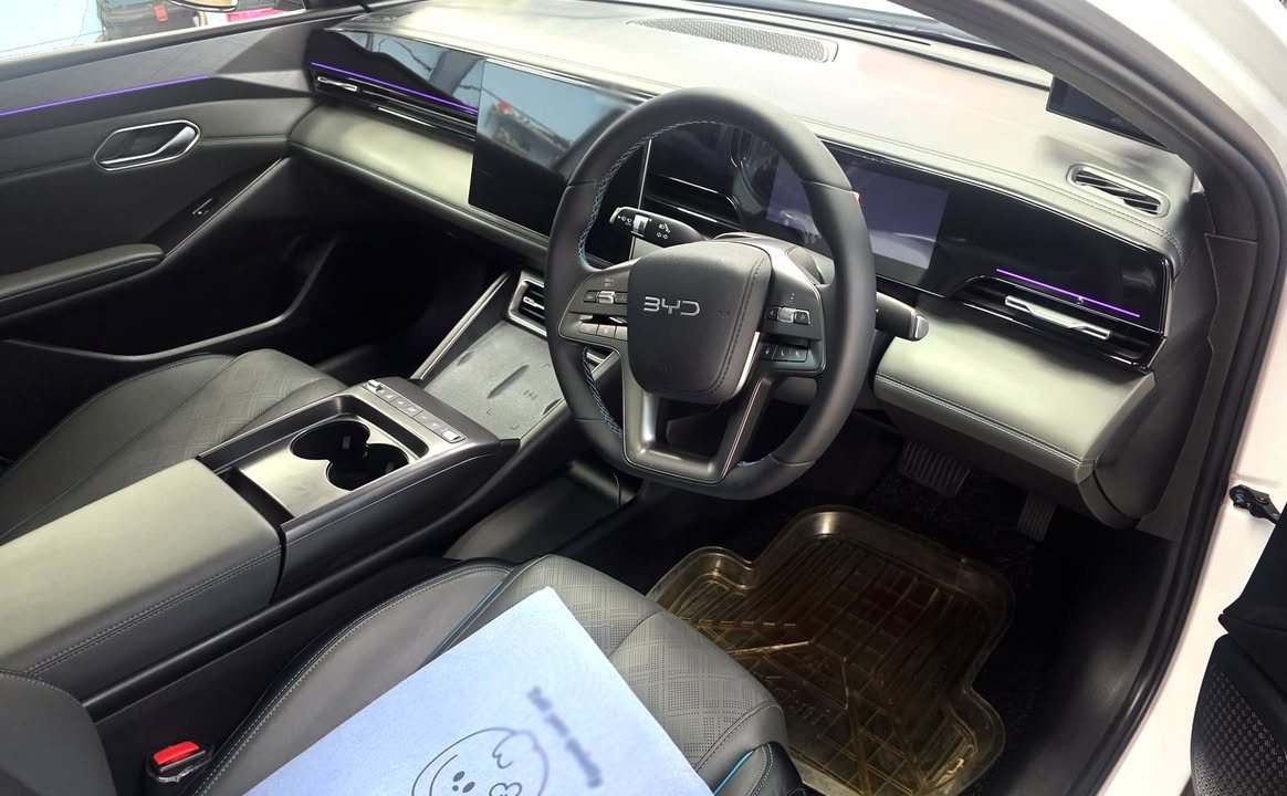 Cabin with dark leather seats, steering wheel and wide dashboard.