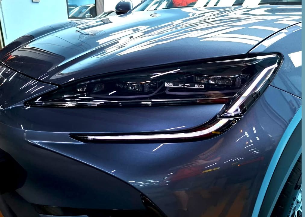 Close-up of the LED headlight and bonnet with workshop lights reflected in the paint.