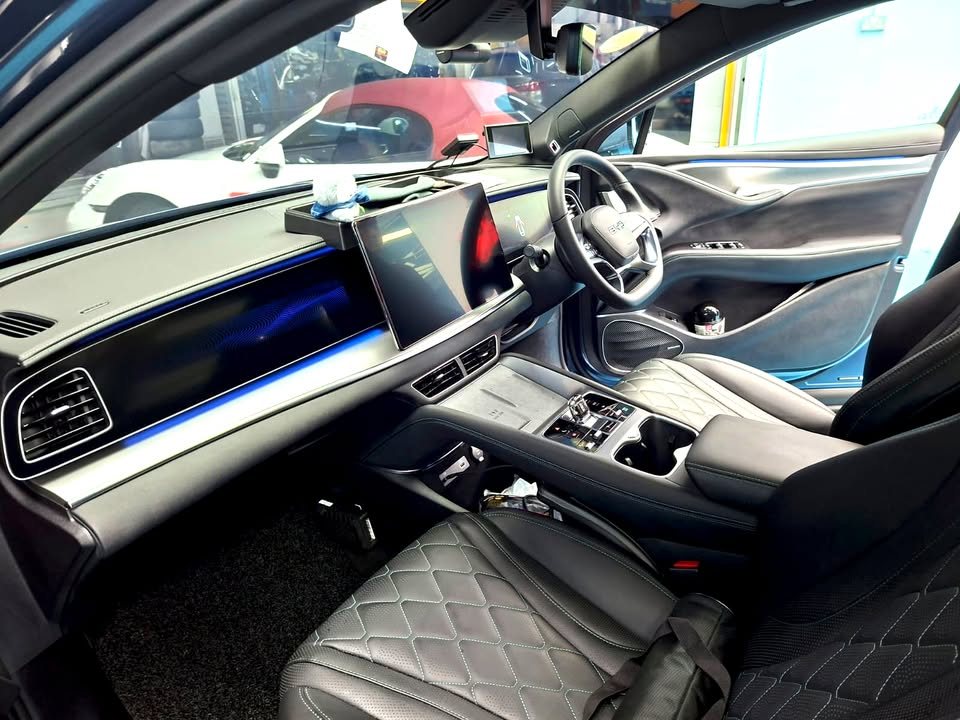 Interior with quilted grey seats, steering wheel and large centre screen.