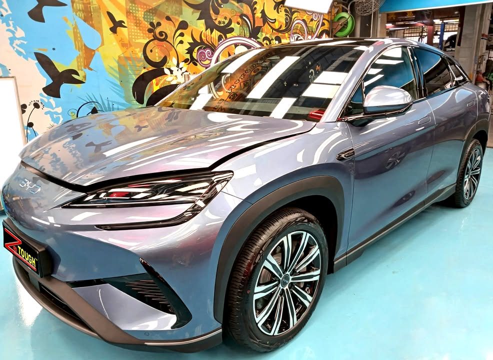 Front three-quarter view of the blue-grey BYD Sealion 7 in the workshop, with two-tone alloy wheels.