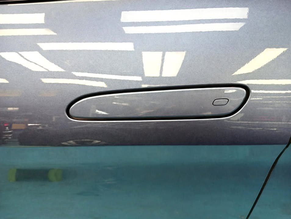 Close-up of the flush door handle on the blue-grey door.