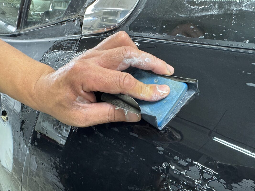 Wet-sanding the body of the Citroen C5 Aircross to smooth the surface.