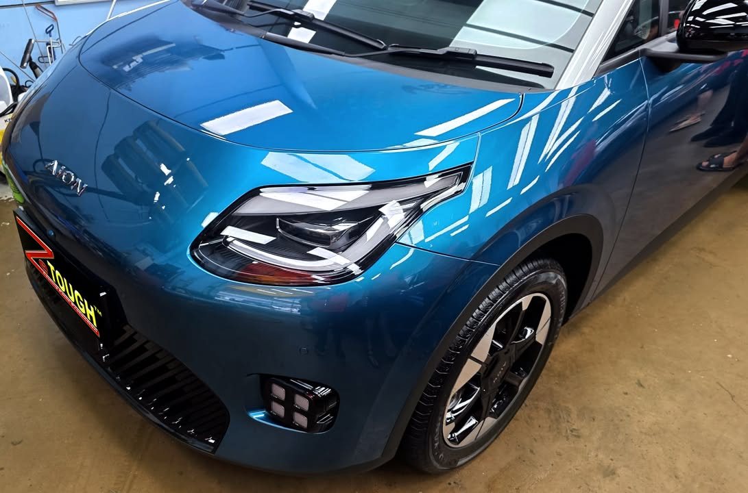 Front of the blue GAC AION showing the headlamp and bonnet.