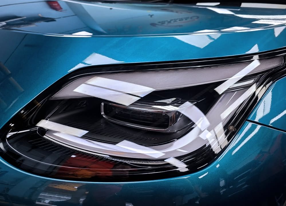 Close-up of the GAC AION headlamp with reflections in the blue paint.