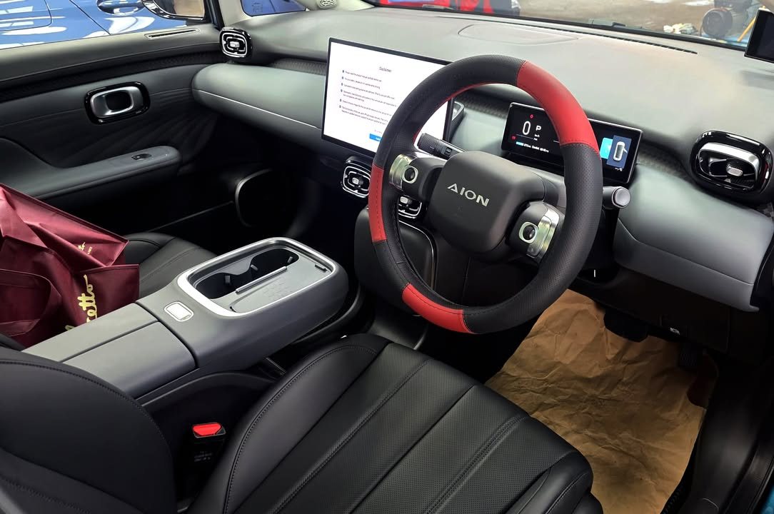 GAC AION cabin with black seats, red and black steering wheel and dashboard screen.