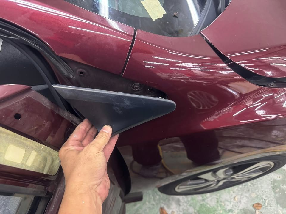 Hand removing a black trim piece from the Honda City's front pillar.