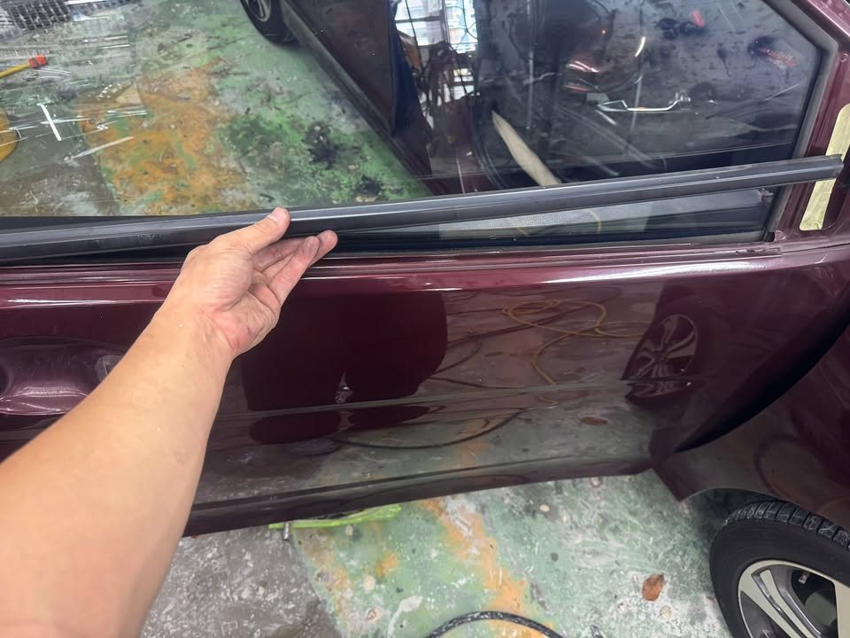 Hand lifting off the window trim strip along the Honda City's door.