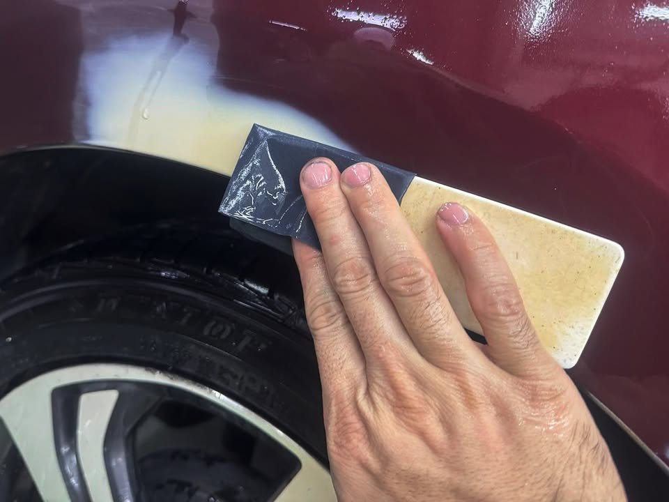 Sanding block on filler over the rear wheel arch of the Honda City.