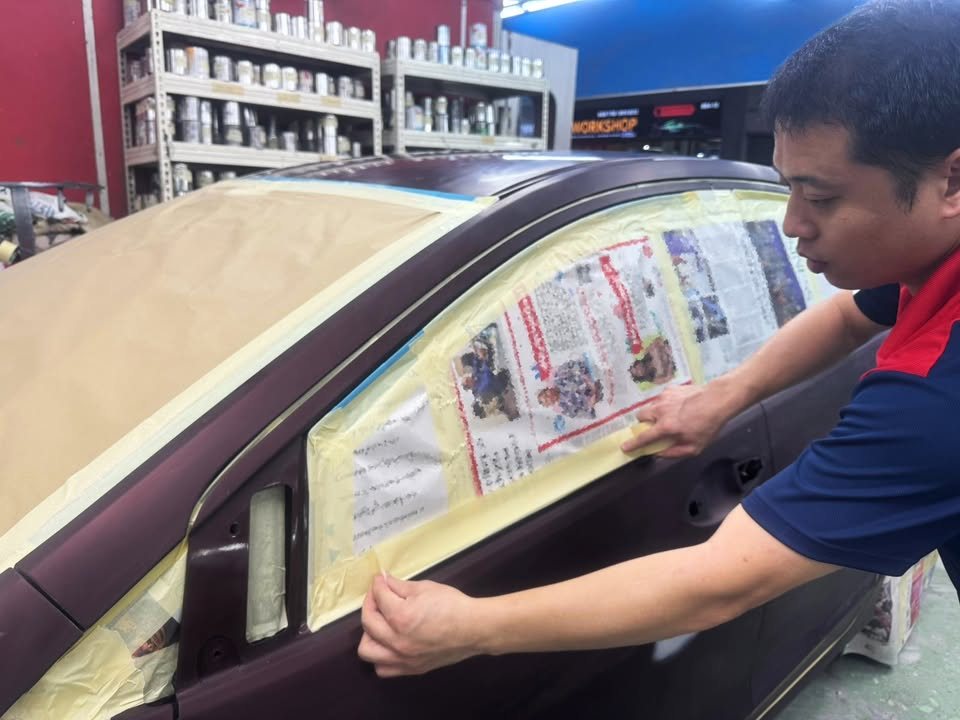 Team member masking the Honda City's window with paper and tape.