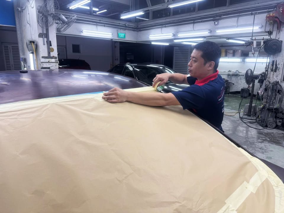 Team member masking the Honda City with paper across the body.