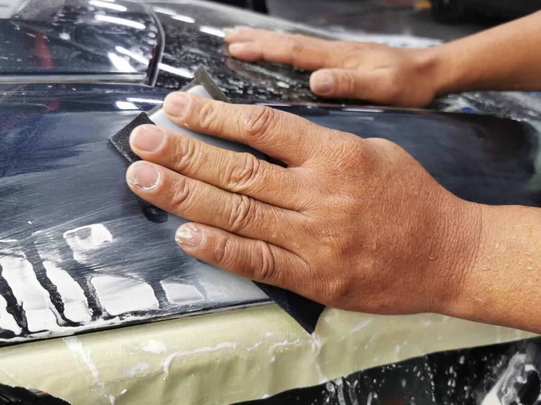 Wet-sanding another panel of the Honda Civic, smoothing ready for primer.